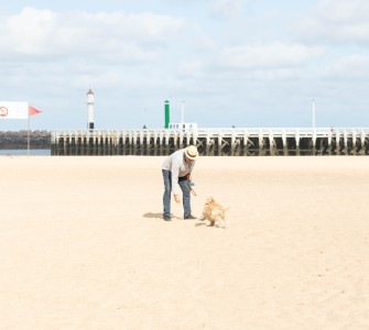 Oudere man speelt met een hond op een verlaten strand