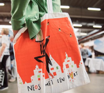 Bezoeker met tas Neos met een hart