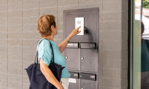 Een dame belt aan bij een appartementsgebouw